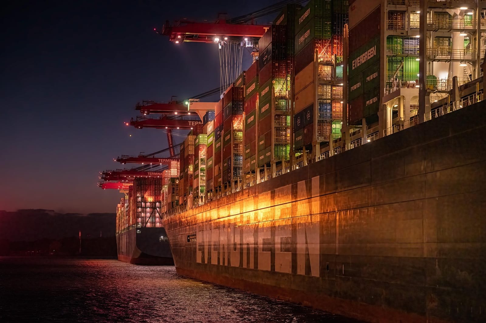 Container cargo ship at an ocean port with stacked shipping containers